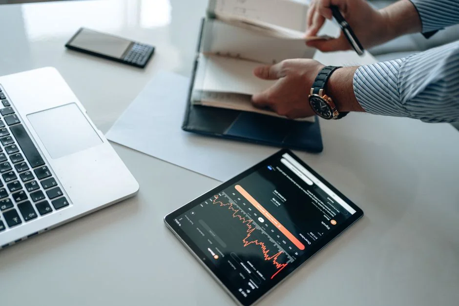 Gros plan sur une personne qui négocie des actions à l’aide d’un smartphone et d’une tablette.